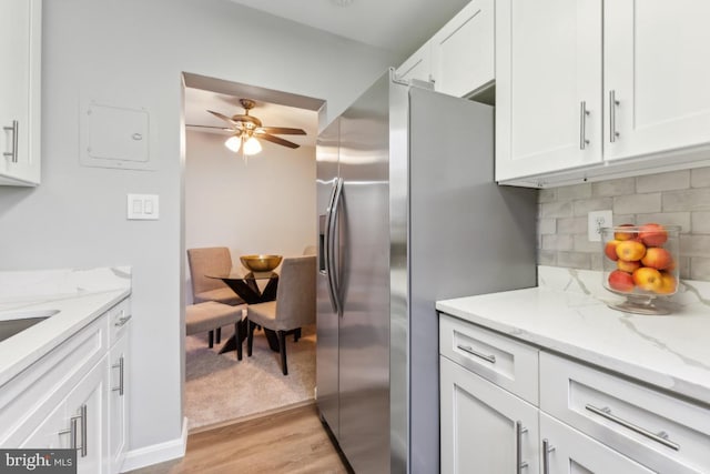 kitchen with light hardwood / wood-style flooring, light stone countertops, decorative backsplash, white cabinetry, and stainless steel fridge with ice dispenser