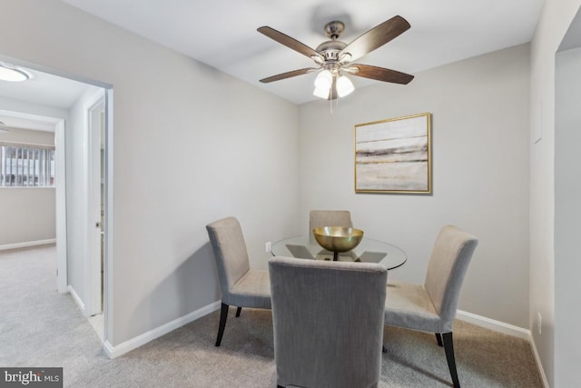 dining area featuring ceiling fan and light colored carpet