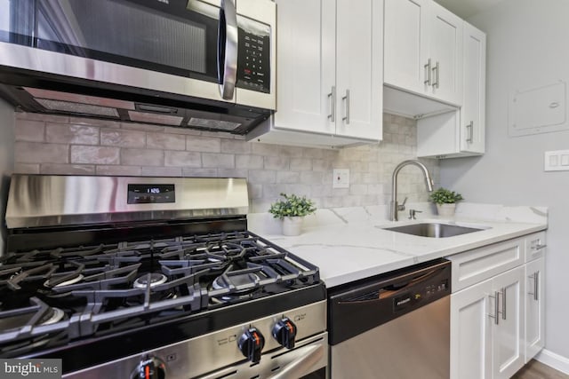 kitchen with sink, backsplash, light stone counters, stainless steel appliances, and white cabinets