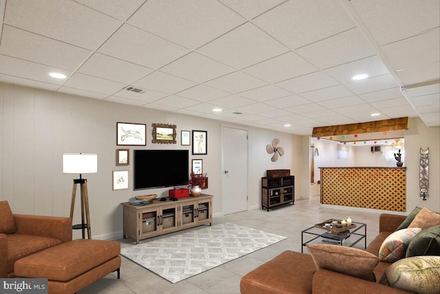 living room with light tile patterned flooring and a paneled ceiling