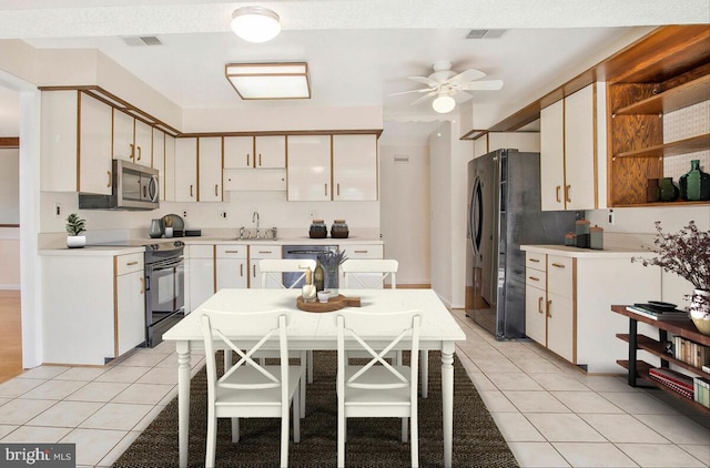 kitchen with sink, white cabinets, light tile patterned floors, ceiling fan, and black appliances