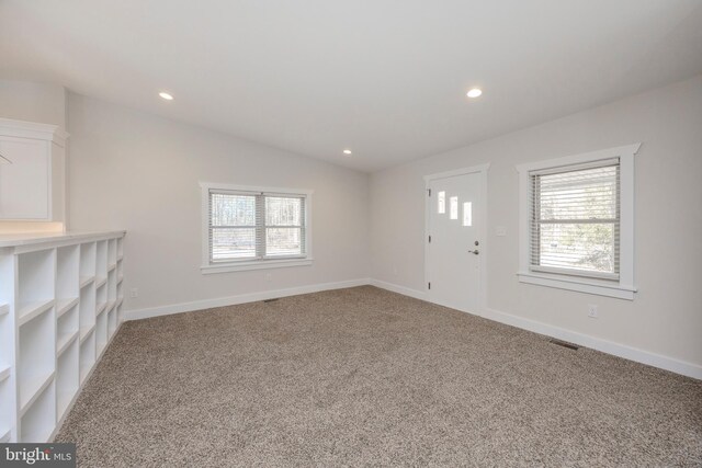 unfurnished living room featuring recessed lighting, light colored carpet, vaulted ceiling, and baseboards