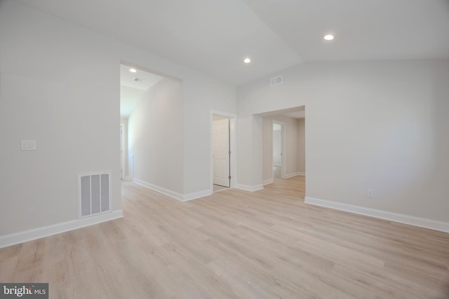 unfurnished room featuring lofted ceiling, baseboards, visible vents, and light wood-style floors