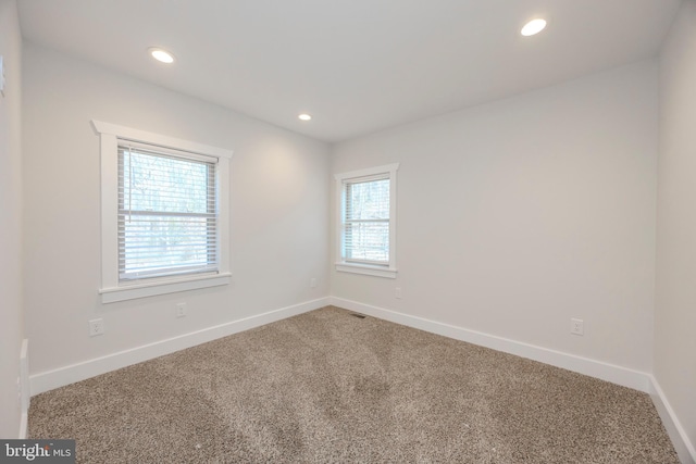 empty room with carpet floors, recessed lighting, visible vents, and baseboards