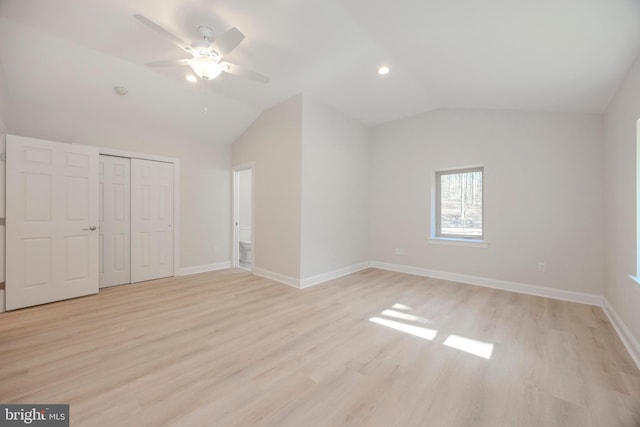 unfurnished bedroom with a closet, vaulted ceiling, light wood-style flooring, and baseboards