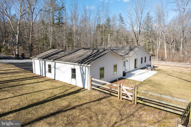 exterior space with a shingled roof, a front yard, a patio, and fence private yard