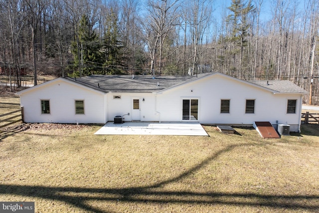 rear view of house featuring central air condition unit, fence, and a yard