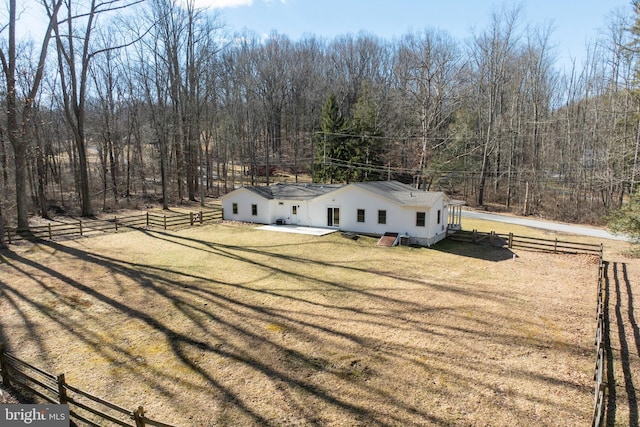 view of front of home featuring a front yard, fence, and a view of trees