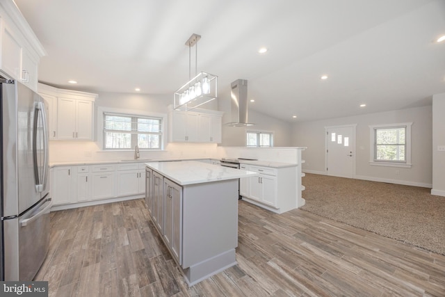 kitchen featuring island exhaust hood, stainless steel appliances, a healthy amount of sunlight, a sink, and a peninsula