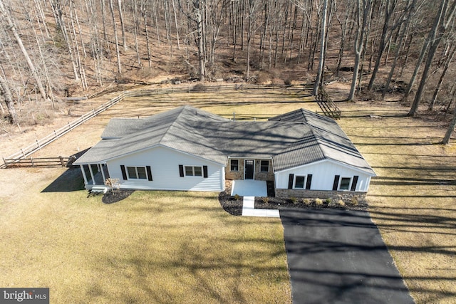 view of front facade featuring stone siding, fence, and a front lawn