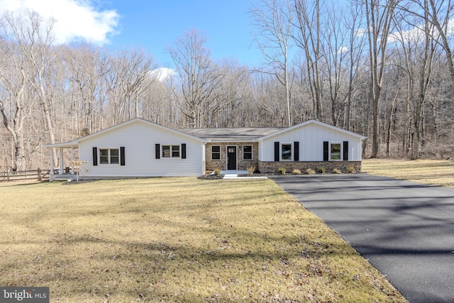 view of front of home featuring stone siding, a front yard, and fence