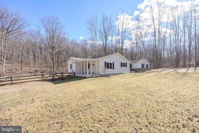 view of front of property with a front yard, covered porch, and fence