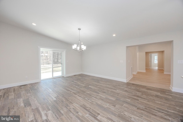 unfurnished room with light wood-style flooring, recessed lighting, a wealth of natural light, and an inviting chandelier