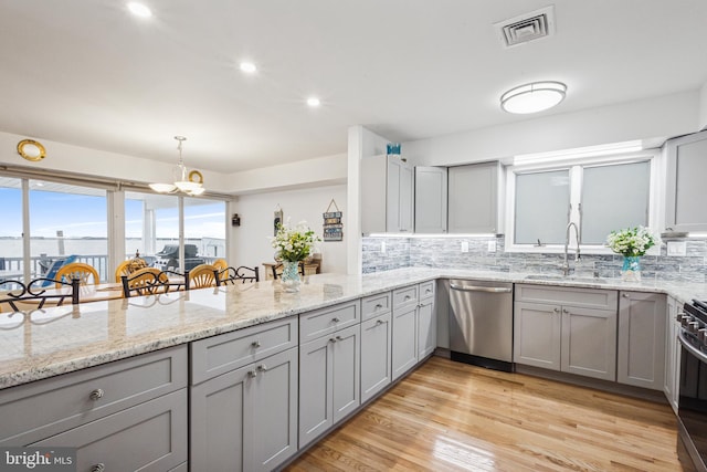 kitchen with visible vents, backsplash, gray cabinetry, a sink, and dishwasher