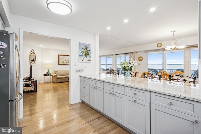 kitchen featuring light wood finished floors, light stone counters, a wealth of natural light, and freestanding refrigerator