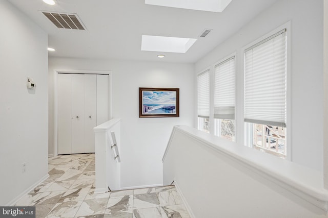 corridor featuring a skylight, marble finish floor, visible vents, and an upstairs landing