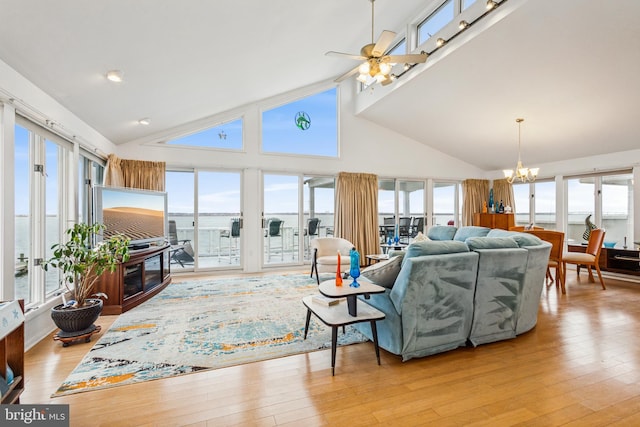 living area with high vaulted ceiling, light wood-style flooring, and ceiling fan with notable chandelier