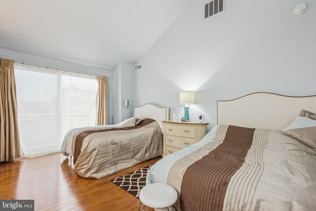 bedroom featuring lofted ceiling, hardwood / wood-style flooring, and visible vents