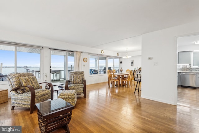 living area featuring light wood-style floors, baseboards, and a chandelier