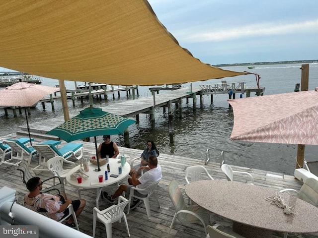 view of dock with outdoor dining space and a water view