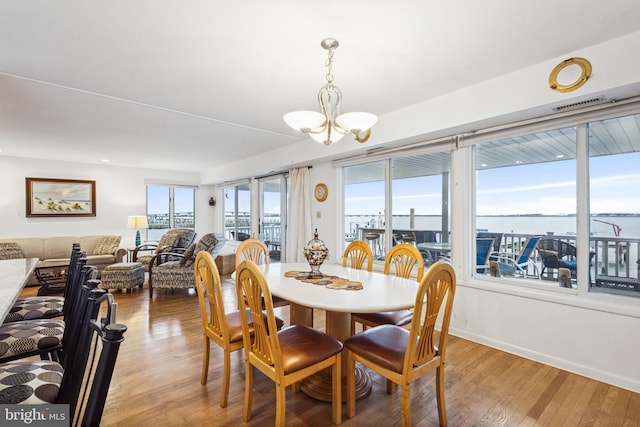 dining space with baseboards, visible vents, a chandelier, and wood finished floors