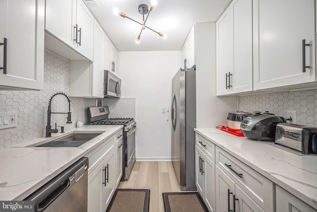 kitchen featuring white cabinetry, appliances with stainless steel finishes, light stone countertops, and sink