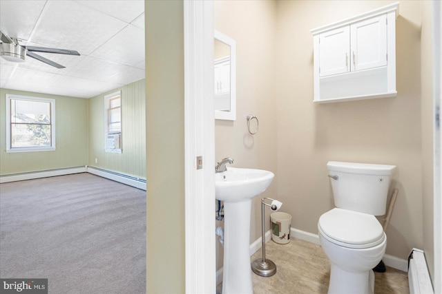 bathroom featuring baseboard heating, ceiling fan, toilet, and sink