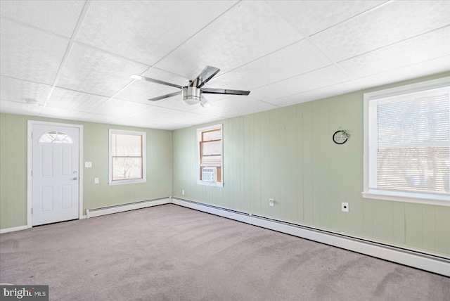 carpeted spare room featuring a baseboard radiator, a drop ceiling, and ceiling fan