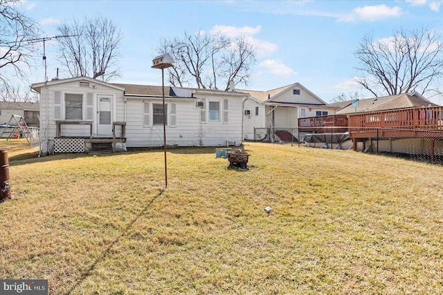 back of property featuring a wooden deck, a yard, and an outdoor fire pit