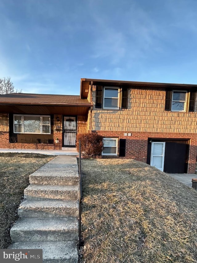 split level home featuring a garage, driveway, and brick siding