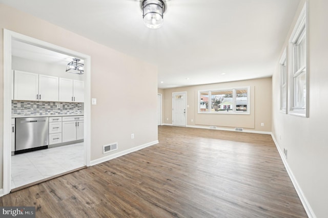 unfurnished living room with visible vents, light wood-style flooring, and baseboards