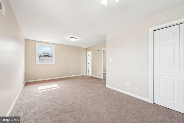 unfurnished bedroom featuring visible vents, a closet, baseboards, and carpet flooring