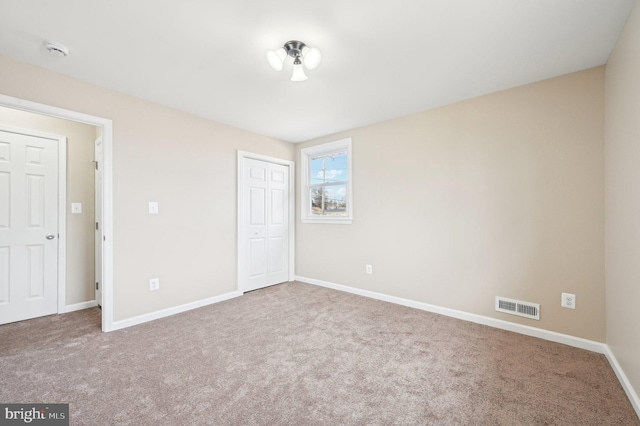 unfurnished bedroom with a closet, carpet, visible vents, and baseboards