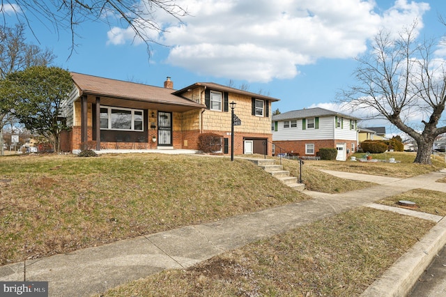 tri-level home with brick siding, a chimney, and a front lawn