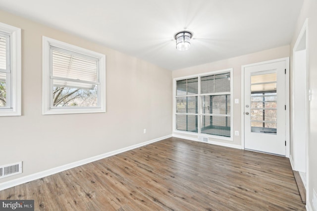 spare room featuring visible vents, baseboards, and wood finished floors