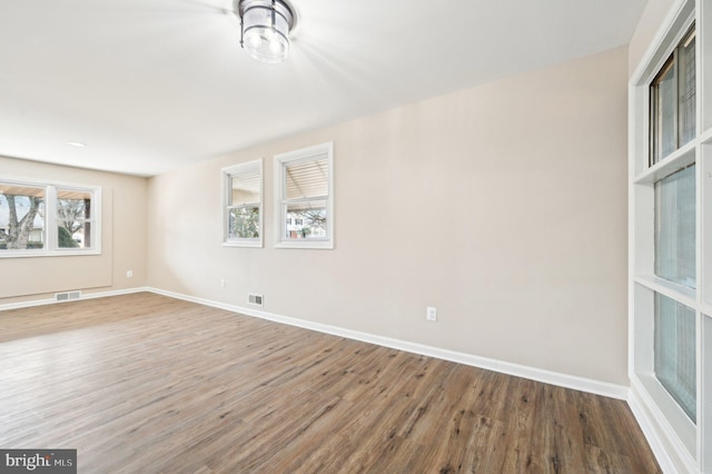 empty room with visible vents, baseboards, and wood finished floors