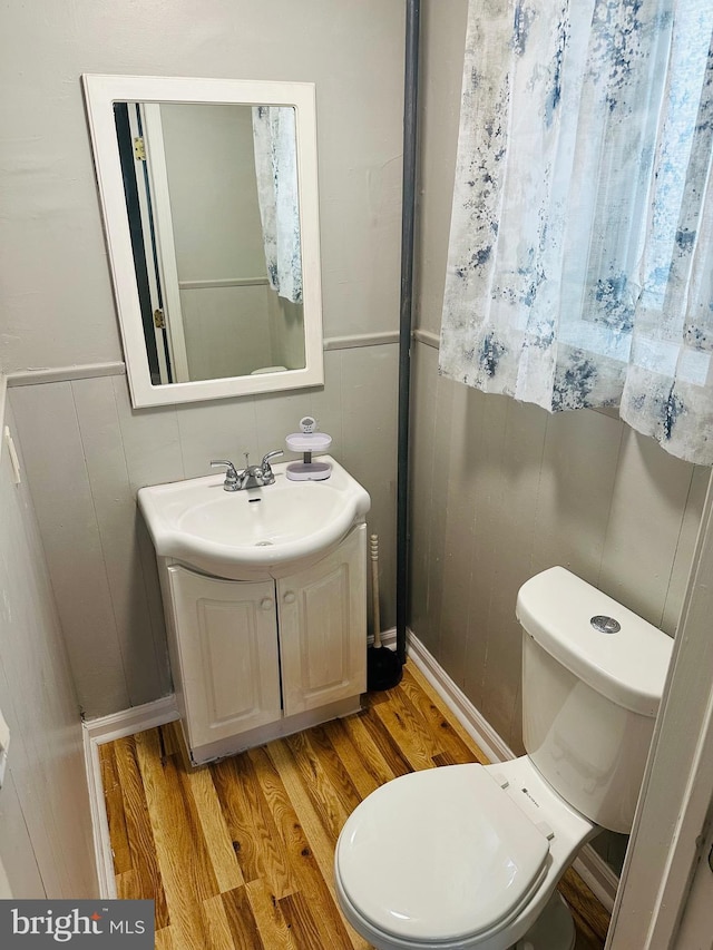 bathroom with wood-type flooring, toilet, and vanity