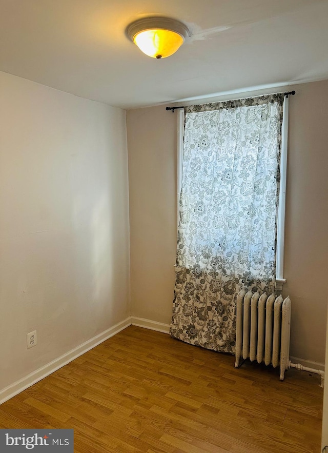 spare room featuring hardwood / wood-style flooring and radiator heating unit