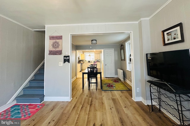 interior space with ornamental molding, radiator heating unit, and light hardwood / wood-style floors