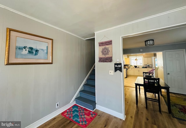 staircase featuring wood-type flooring and ornamental molding