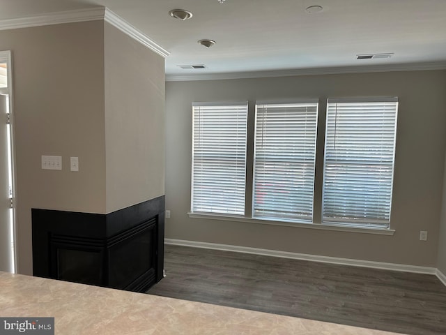 interior space with ornamental molding, visible vents, a multi sided fireplace, and wood finished floors