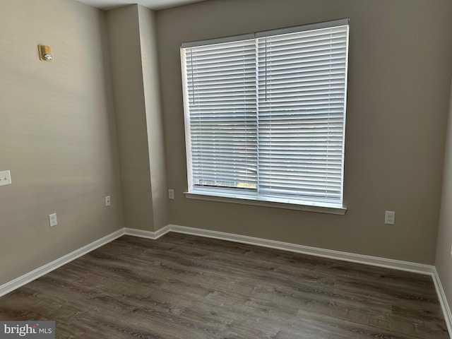 empty room with dark wood-type flooring and baseboards