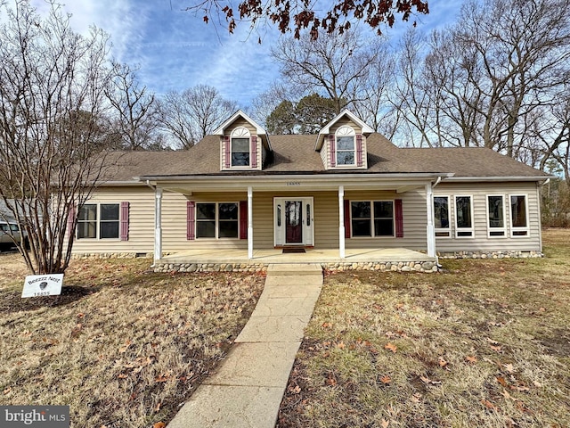 cape cod house with a front lawn and covered porch