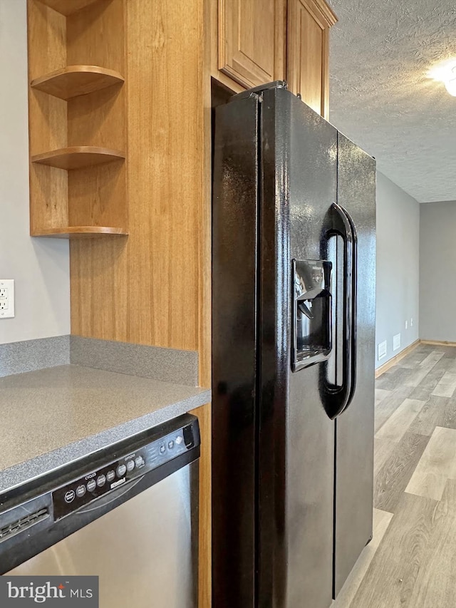 kitchen featuring dishwasher, black fridge, light wood-type flooring, and a textured ceiling