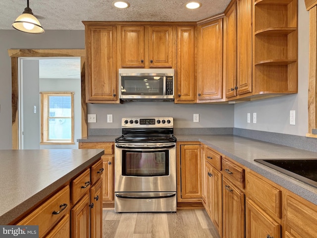 kitchen with pendant lighting, appliances with stainless steel finishes, light hardwood / wood-style floors, and a textured ceiling