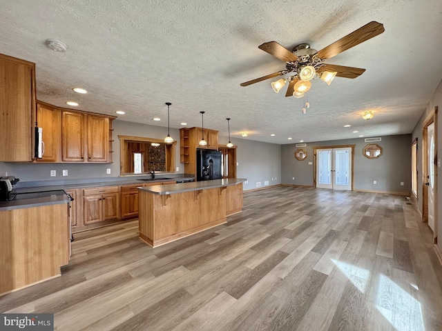 kitchen featuring hanging light fixtures, a center island, black fridge with ice dispenser, french doors, and light wood-type flooring