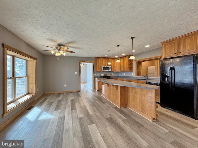 kitchen with sink, a kitchen breakfast bar, hanging light fixtures, a center island, and stainless steel appliances