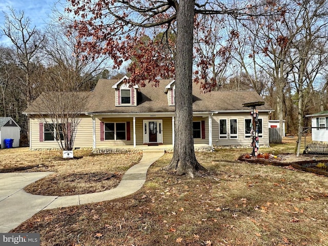 new england style home featuring a front yard and covered porch