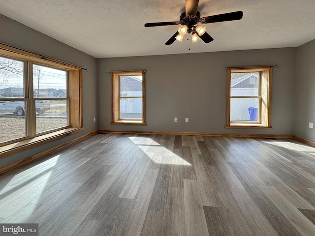 empty room with ceiling fan, a textured ceiling, and light hardwood / wood-style flooring