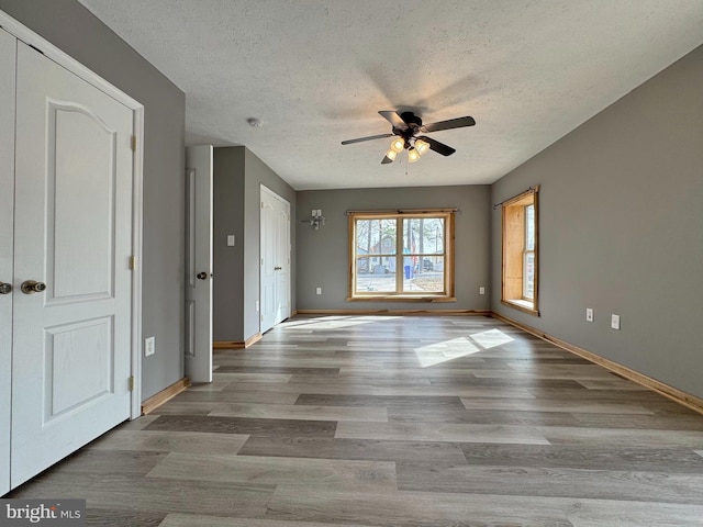 empty room with ceiling fan, light hardwood / wood-style flooring, and a textured ceiling